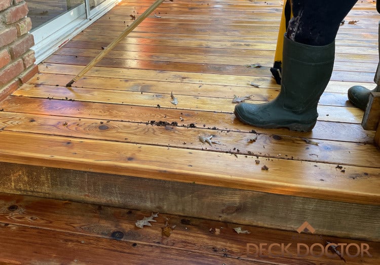Image Of Space Between Deck Floor Boards Being Cleaned By Hand.